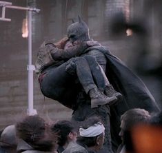 a man dressed as batman being carried on his back