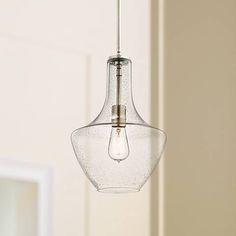 a glass light fixture hanging from a ceiling in a room with a mirror behind it