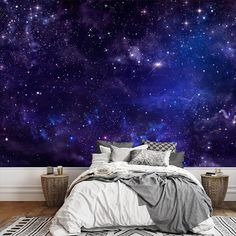 a bed with pillows and blankets in front of a wall that has stars on it