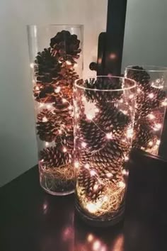 pine cones are placed in glass vases with lights on the inside and around them