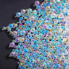 many different colored beads on a black surface with white and blue dots in the middle