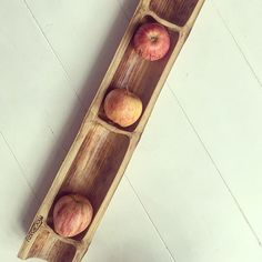 three apples in a wooden tray on the floor