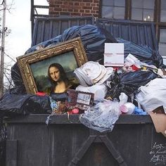 there is a painting on the back of a dumpster full of trash and other items