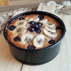 a cake with bananas and blueberries in a black pan on a wooden table top