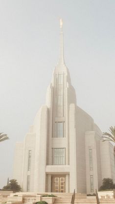 a large white building with stairs leading up to the front door and side entrance on a foggy day