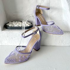 a pair of purple high heel shoes sitting on top of a white floor next to a pile of rocks