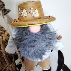 a close up of a stuffed animal wearing a hat and holding a stick in its hand