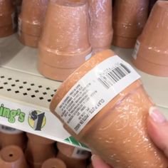 a person is holding a plastic cup in front of rows of cups on display at a store