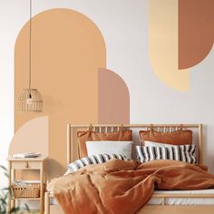 a bed with pillows and blankets on it in front of a wall painted with geometric shapes