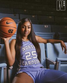 a woman holding a basketball while sitting in a stadium