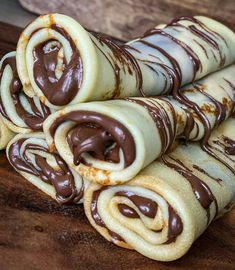 chocolate covered rolled up desserts sitting on top of a wooden table