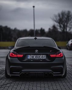 the back end of a black car parked in a parking lot