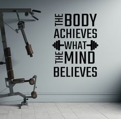 a gym wall decal that says the body achieves what the mind belies