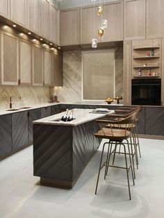 a kitchen with an island and bar stools in the center, surrounded by wooden cabinets