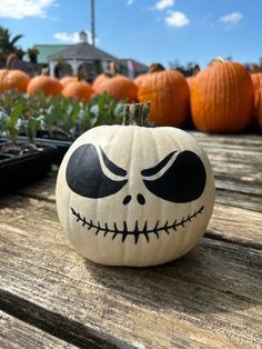 a jack - o'- lantern pumpkin sitting on top of a wooden table next to other pumpkins