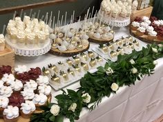 a table topped with lots of cupcakes covered in white frosting and flowers