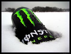 a close up of a bottle in the snow with green and black paint on it