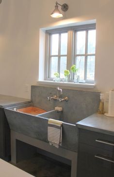 a kitchen sink sitting under a window next to a counter top with a towel hanging on it