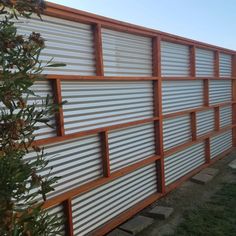 a metal fence with wooden slats on top and grass in the foreground next to it