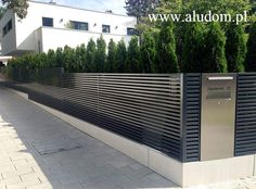 a large metal fence sitting on top of a sidewalk next to a lush green forest