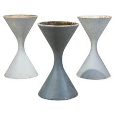 three white vases sitting next to each other on a white surface with dirt in them