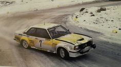 a yellow and white car driving down a snow covered road