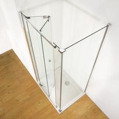 a glass shower stall with wooden flooring and white walls in an empty room, viewed from above