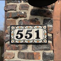 a house number sign mounted to the side of a brick building