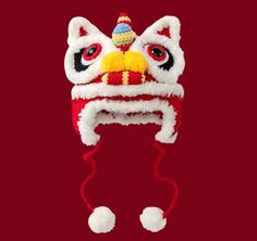 a red and white knitted hat with a cat on it's head, hanging from the side