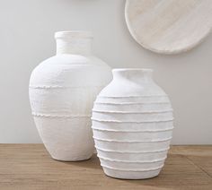 two white vases sitting on top of a wooden table