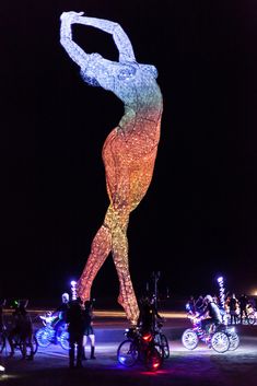 a woman standing on top of a bike in front of a display with lights all over her body