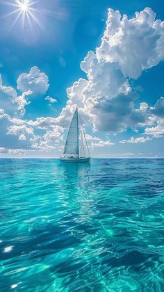 a sailboat floating in the ocean under a blue sky with clouds and sunburst