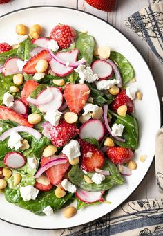 a salad with strawberries, radishes, and cheese on a white plate