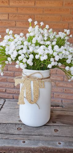 a white mason jar filled with flowers on top of a wooden table