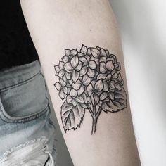 a black and white photo of a flower tattoo on the left arm, with leaves around it