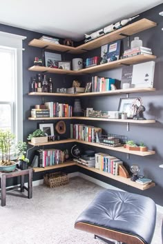 a corner book shelf with many books on it in a living room next to a window