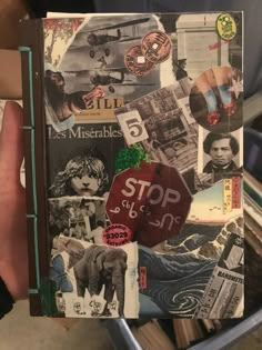 a person holding up a book with pictures and stickers all over it's cover