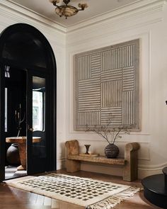 an entryway with a rug, table and vases on the floor next to it