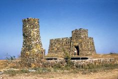 an old stone building sitting on top of a dry grass field