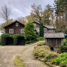 a house in the middle of a gravel road with trees and bushes around it on either side