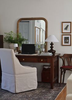 a white chair sitting in front of a desk with a laptop computer on top of it