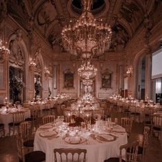 a fancy dining room with chandeliers and white tablecloths on the tables