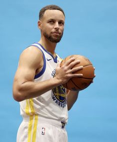 a man holding a basketball in his right hand and looking at the camera with an intense look on his face