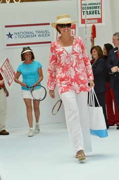 a woman is walking down the runway with her tennis racket in hand and two other people are standing behind her