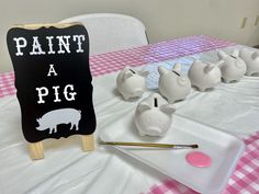 some pig figurines are on a table with a sign that says paint a pig