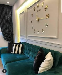 a green couch sitting in front of a large clock mounted to the side of a wall