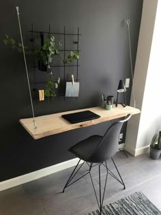 a desk with two chairs and a laptop on it in front of a gray wall