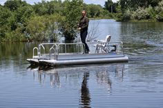 a man standing on top of a boat in the middle of a body of water