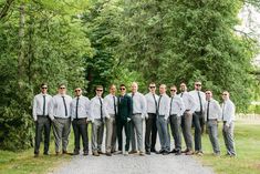 a group of men standing next to each other in front of some trees and grass