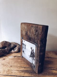 an old photo frame sitting on top of a wooden table next to a driftwood sculpture